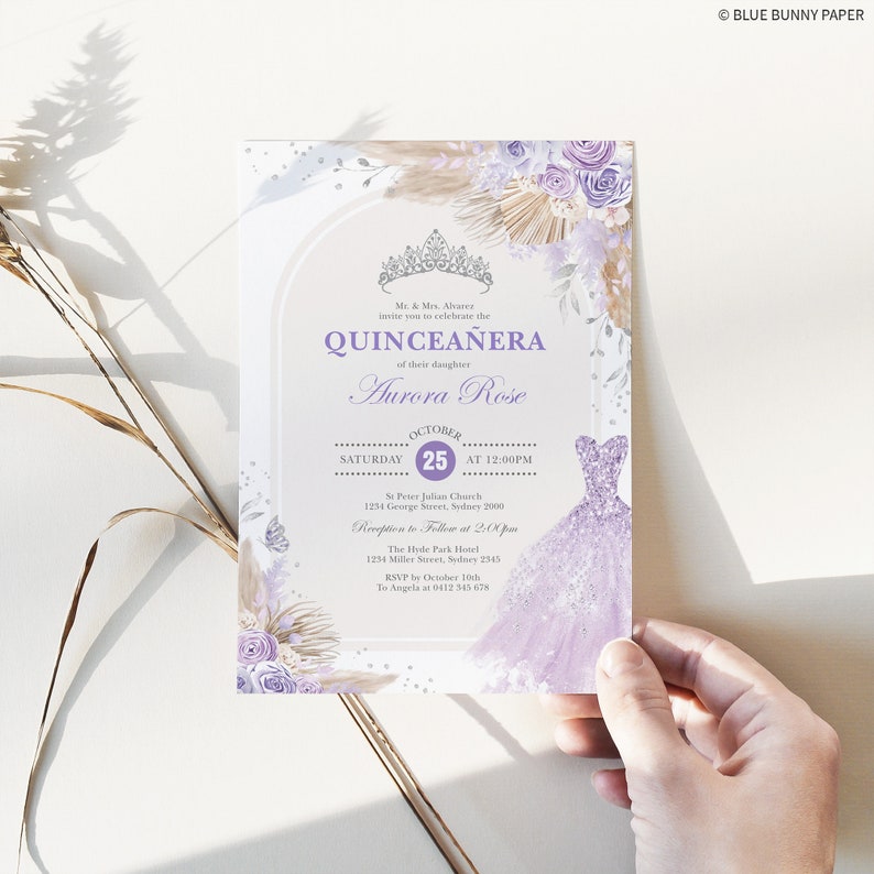 May include: Purple and gold quincea&ntilde;era invitation with a crown, flowers, and a sparkly purple dress. The invitation includes the date, time, and location of the event. RSVP information is also included.