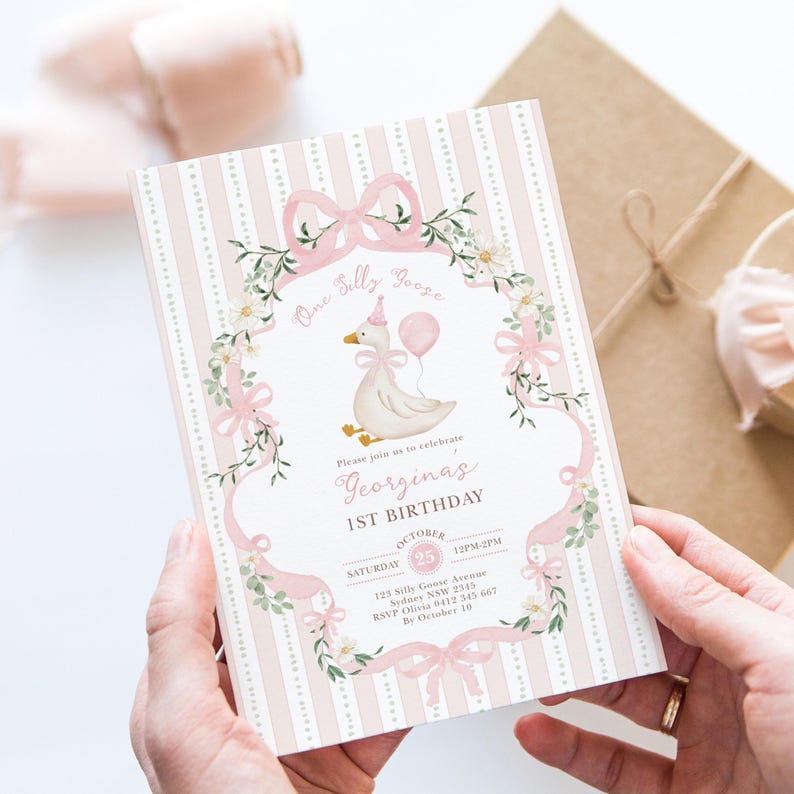 K&ouml;nnte beinhalten: Eine rosa-wei&szlig;e Geburtstagseinladung mit einer Cartoon-Gans, die einen Ballon h&auml;lt. Die Einladung enth&auml;lt den Text "One Silly Goose" und "Georgina's 1ST BIRTHDAY". Die Einladung ist mit Blumen- und Schleifenakzenten verziert.