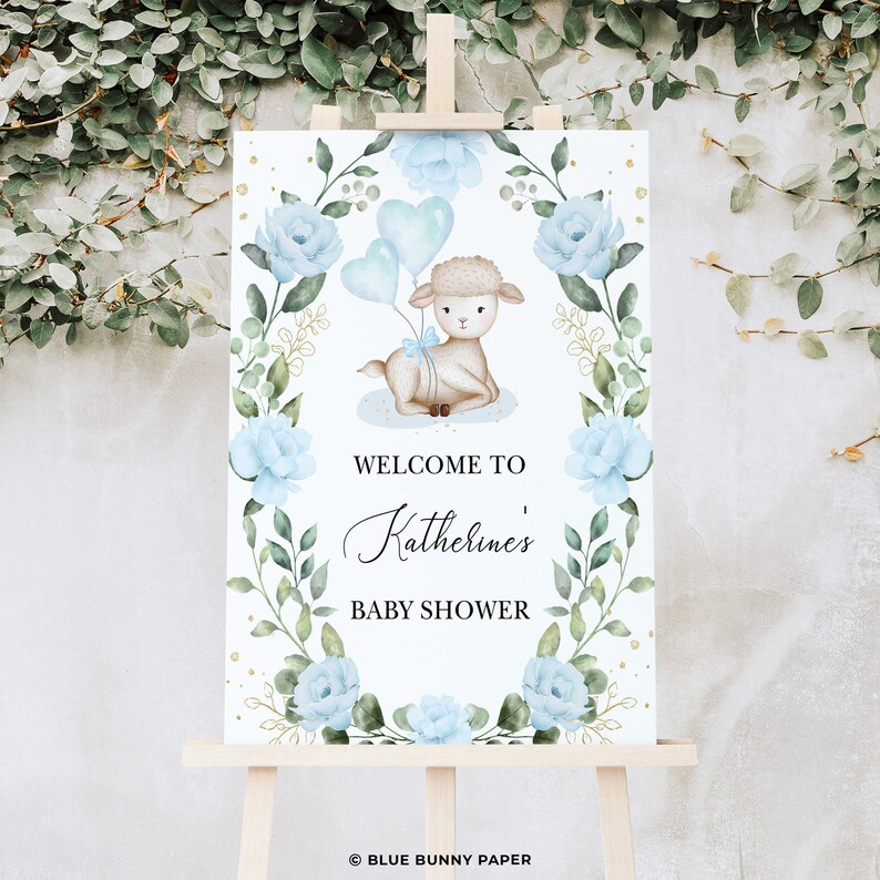 May include: A welcome sign for a baby shower with a blue and green floral wreath, a cute lamb holding blue balloons, and the text "Welcome to Katherine's Baby Shower".