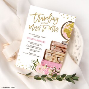 May include: A bridal shower invitation with a gold glitter design that says "Traveling from Miss to Mrs". The invitation features a pink and gold globe, pink and brown suitcases, and pink flowers.