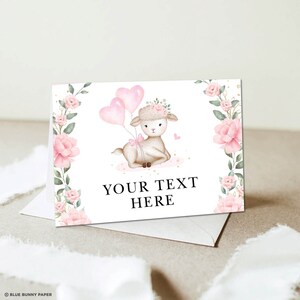 Op de afbeelding: Een wit lam met roze ballonnen en een bloemenkrans. Het lam zit op een roze en gouden achtergrond. De tekst "YOUR TEXT HERE" staat onder het lam.