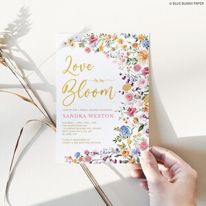 Peut inclure: Une invitation de f&ecirc;te pr&eacute;nuptiale florale avec une inscription dor&eacute;e "Love is in Bloom" et une banni&egrave;re rose avec le nom "Sandra Weston". L'invitation comprend les d&eacute;tails de la f&ecirc;te, y compris la date, l'heure, le lieu et les informations RSVP.