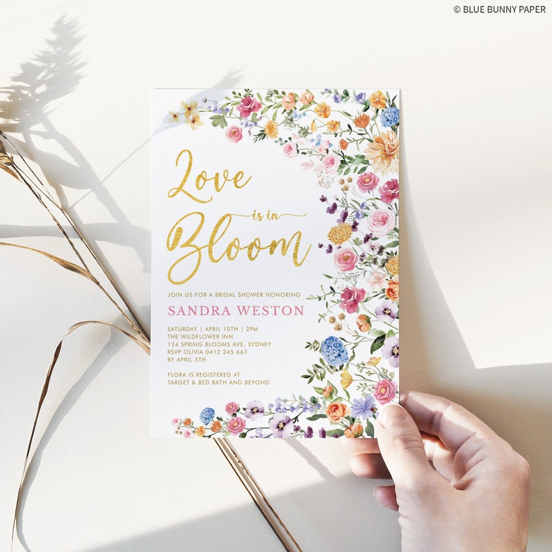 Peut inclure: Une invitation de f&ecirc;te pr&eacute;nuptiale florale avec une inscription dor&eacute;e "Love is in Bloom" et une banni&egrave;re rose avec le nom "Sandra Weston". L'invitation comprend les d&eacute;tails de la f&ecirc;te, y compris la date, l'heure, le lieu et les informations RSVP.