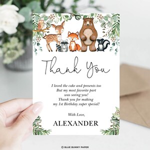 K&ouml;nnte beinhalten: Eine Wald-Danksagungskarte mit einer Aquarell-Illustration eines Rehs, Fuchses, Waschb&auml;ren, B&auml;ren und Stinktiers. Die Karte enth&auml;lt den Text "Danke" in einer handschriftlichen Schriftart und die Nachricht "Ich habe den Kuchen und die Geschenke auch geliebt Aber mein Lieblingsteil war, dich zu sehen! Danke, dass du meinen 1. Geburtstag so besonders gemacht hast! Mit Liebe, ALEXANDER".