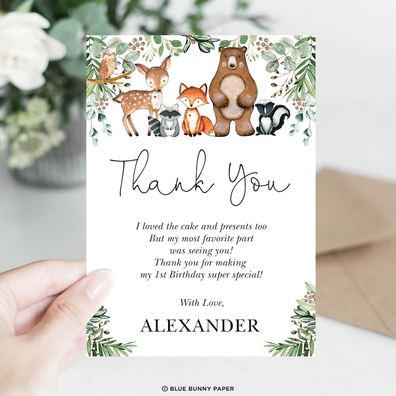 K&ouml;nnte beinhalten: Eine Wald-Danksagungskarte mit einer Aquarell-Illustration eines Rehs, Fuchses, Waschb&auml;ren, B&auml;ren und Stinktiers. Die Karte enth&auml;lt den Text "Danke" in einer handschriftlichen Schriftart und die Nachricht "Ich habe den Kuchen und die Geschenke auch geliebt Aber mein Lieblingsteil war, dich zu sehen! Danke, dass du meinen 1. Geburtstag so besonders gemacht hast! Mit Liebe, ALEXANDER".