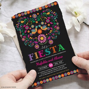 May include: A black invitation with a colorful floral heart design and the text "Let's Fiesta" in rainbow colors. The invitation is for a couples shower celebrating Mafalda and Alvaro. The event is scheduled for October 30th from 2 PM to 4 PM at El Camino Cantina Mexican Restaurant. The address is 125 Fiesta Parade, Sydney NSW 2000. RSVP to Beatriz at 0412 345 676 by 08.05.20XX. The couple is registered at Myer, David Jones and Target.