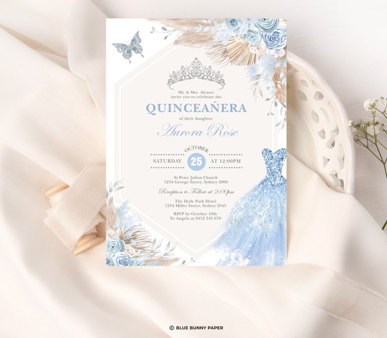 May include: A blue and white quincea&ntilde;era invitation with a floral design and a crown. The invitation includes the text "Quincea&ntilde;era" and "Aurora Rose". The date of the event is October 25th. The invitation also includes the location of the event, St. Peter Julian Church, and the time, 12:00 PM.