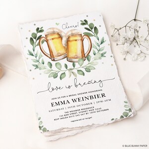 K&ouml;nnte beinhalten: Eine Aquarell-Illustration von zwei Bierkr&uuml;gen mit gr&uuml;nen Bl&auml;ttern und dem Text "love is brewing" auf wei&szlig;em Hintergrund. Der Text "Join us for a bridal shower honoring Emma Weinbier" befindet sich unter der Illustration. Datum und Uhrzeit der Veranstaltung sind unter dem Namen aufgef&uuml;hrt. Der Text "The Weinbier Residence" ist unter dem Datum und der Uhrzeit aufgef&uuml;hrt. Die Adresse und die RSVP-Informationen sind unter der Residenz aufgef&uuml;hrt. Der Text "registered at target" ist unter den RSVP-Informationen aufgef&uuml;hrt.
