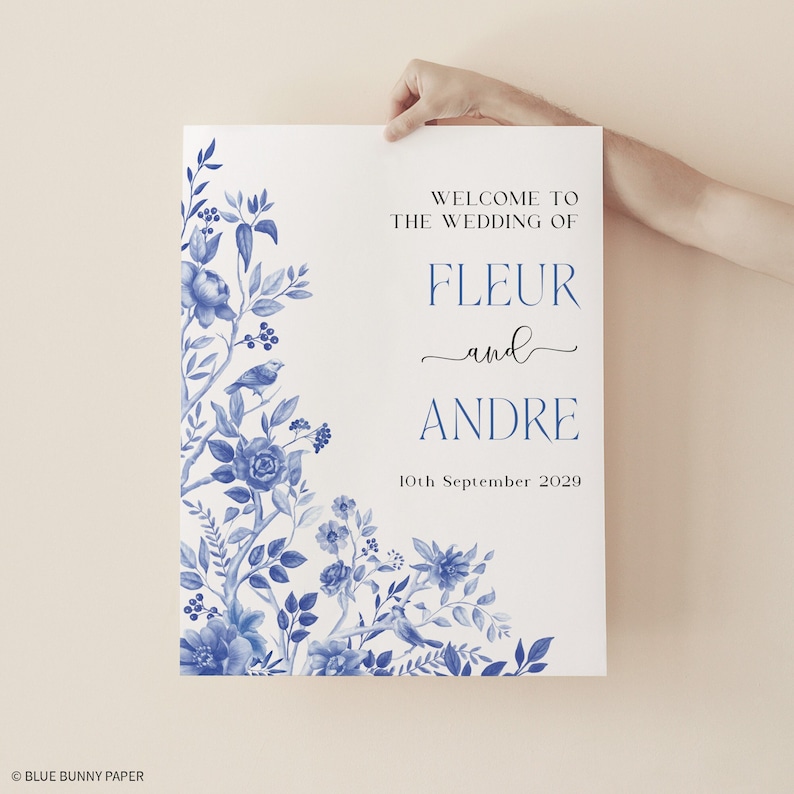 May include: A white wedding welcome sign with blue floral designs and the text "Welcome to the wedding of Fleur and Andre 10th September 2029".