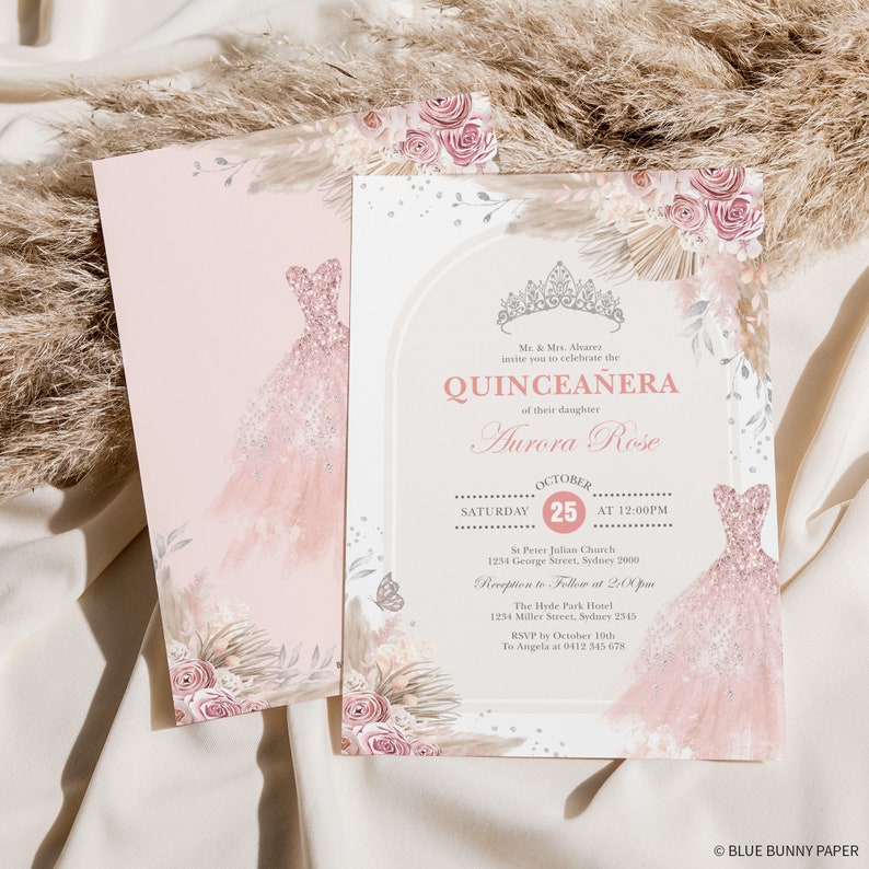 May include: Pink and gold Quincea&ntilde;era invitation with a floral design and a crown. The invitation includes the date, time, and location of the event. The text reads "Mr. & Mrs. Alvares invite you to celebrate the Quincea&ntilde;era of their daughter Aurora Rose. October 25 at 12:00pm. St Peter Julian Church 1234 George Street, Sydney 2000. Reception to Follow at 2:00pm. The Hyde Park Hotel 1254 Miller Street, Sydney 2345. RSVP by October 10th to Angela at 0412 345 678. Blue Bunny Paper."