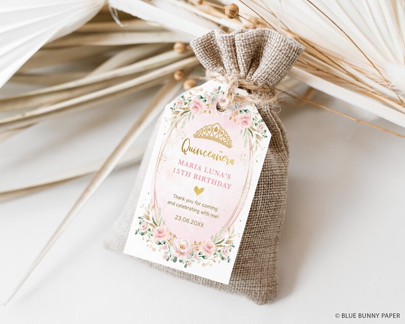 May include: A pink and gold favor tag with a floral design and the text "Quincea&ntilde;era Maria Luna's 15th Birthday" and "Thank you for coming and celebrating with me! 23.06.20XX".
