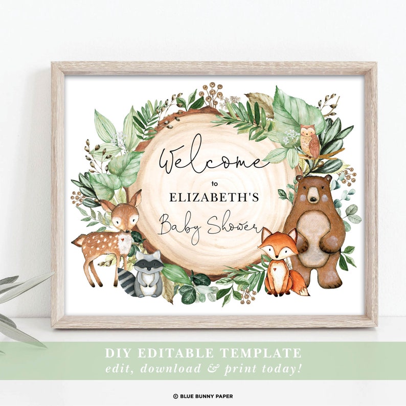 May include: A printable welcome sign for a baby shower with a woodland theme. The sign features a woodgrain circle with a green leafy wreath, a bear, a fox, a deer, a raccoon, and an owl. The text on the sign reads "Welcome to Elizabeth's Baby Shower".