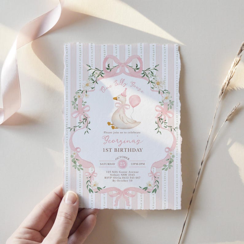 K&ouml;nnte beinhalten: Eine rosa-wei&szlig;e Geburtstagseinladung mit einem skurrilen Design. Die Einladung zeigt eine Cartoon-Gans, die einen Ballon h&auml;lt, umgeben von floralen und Schleifen-Akzenten. Der Text enth&auml;lt "One Silly Goose" und "1st Birthday".