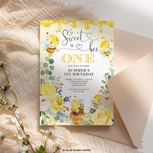 K&ouml;nnte beinhalten: Eine gelbe und wei&szlig;e Einladung mit einem Bienen-Motiv. Die Einladung lautet "So Sweet to Bee One" und zeigt einen Honigtopf mit einer Biene darauf. Sie lautet "Bitte feiern Sie mit uns den 1. Geburtstag von Summer" und enth&auml;lt Datum, Uhrzeit, Ort und RSVP-Informationen.