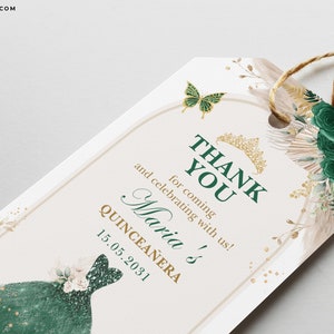 May include: A Quincea&ntilde;era thank you tag with a green and gold design. The tag features the text "THANK YOU" and "Maria's Quincea&ntilde;era 15.05.2031". It is decorated with a butterfly, a crown, and floral elements.