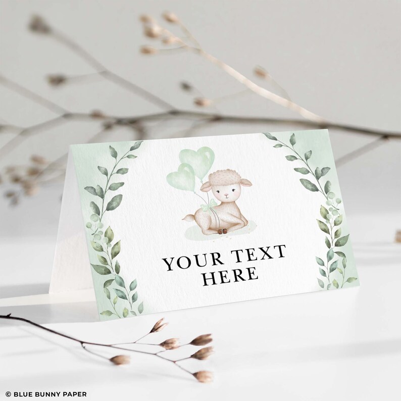 Puede incluir: Una tarjeta de lugar imprimible verde y blanca con una ilustraci&oacute;n de acuarela de un cordero sosteniendo globos verdes. El texto "YOUR TEXT HERE" est&aacute; impreso en negro.