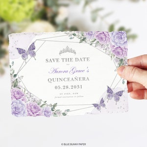 May include: Save the date card with a silver geometric frame and floral design. The card features a purple butterfly, a silver crown, and the text "Save the Date for Aurora Grace's Quincea&ntilde;era 05.28.2031 ST IVES, NSW formal invitation to follow."