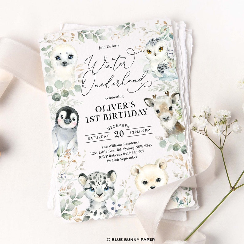 Peut inclure: Une invitation &agrave; un premier anniversaire sur le th&egrave;me du pays des merveilles d'hiver avec une illustration aquarelle d'un pingouin, d'un ours polaire, d'un hibou, d'un phoque et d'un renne. L'invitation comprend le texte "Join Us for a Winter Wonderland - celebrating - Oliver's 1st Birthday December 20 12PM-2PM The Williams Residence 1234 Little Bear Rd, Sydney NSW 2345 RSVP Rebecca 0412 345 667 By 10th September &copy; BLUE BUNNY PAPER".