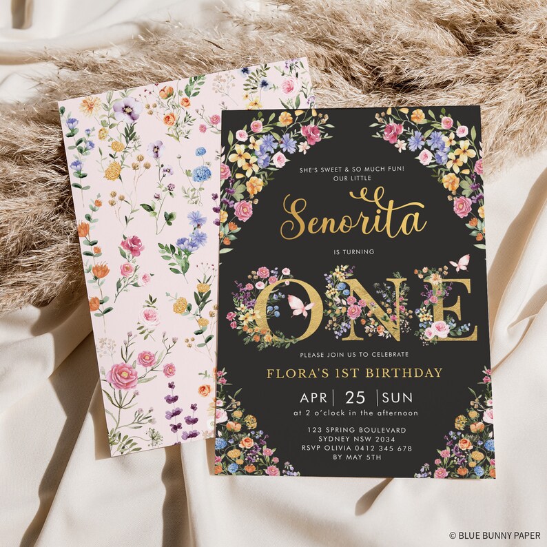 May include: A floral-themed first birthday invitation for a girl named Flora. The invitation features a black background with gold lettering and a large number "ONE" decorated with colourful flowers. The text reads "She's sweet & so much fun! Our little Senorita is turning one. Please join us to celebrate Flora's 1st birthday. Apr 25 Sun at 2 o'clock in the afternoon. 123 Spring Boulevard Sydney NSW 2034. RSVP Olivia 0412 345 678 by May 5th. &copy; Blue Bunny Paper."