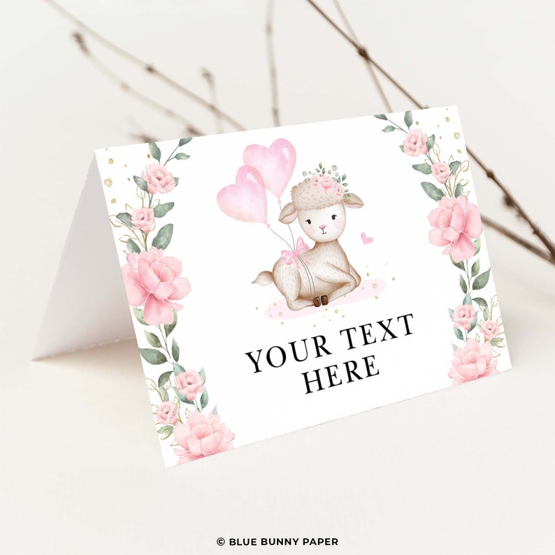 Op de afbeelding: Een witte kaart met een roze bloemrand en een schattig cartoonlam dat roze hartballonnen vasthoudt. De tekst "YOUR TEXT HERE" staat op de kaart gedrukt.