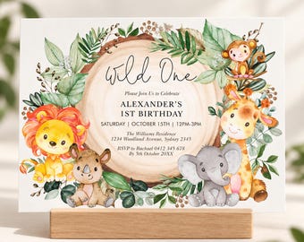 May include: A rectangular birthday invitation card featuring a watercolor illustration of a tree slice surrounded by green leaves and cute animals including a lion, rhino, elephant, giraffe, and monkey. The text reads Wild One, Alexander's 1st Birthday.