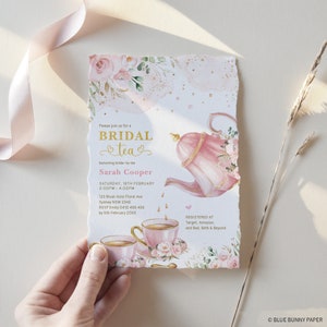 May include: A pink and gold bridal shower invitation with a teapot and teacups. The invitation reads "Please join us for a Bridal Tea honoring bride-to-be Sarah Cooper" and includes the date, time, address, RSVP information, and a list of stores where gifts can be registered.