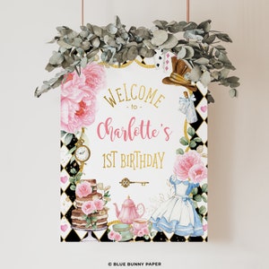 Op de afbeelding: Een decoratief bord met de tekst "Welcome to Charlotte's 1st Birthday" in goud en roze. Het bord toont illustraties van bloemen, een taart, een theepot en elementen uit Alice in Wonderland, tegen een zwart-witte geruite achtergrond.