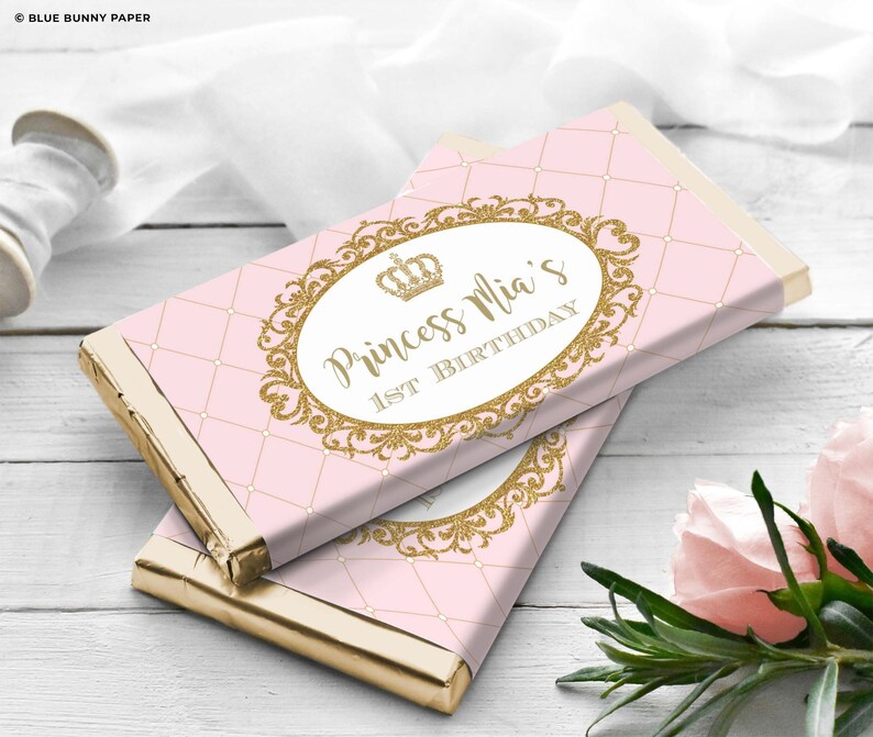 K&ouml;nnte beinhalten: Rosa-goldene Schokoladentafel-Verpackung mit einer goldenen Krone und dem Text "Princess Mia's 1st Birthday".