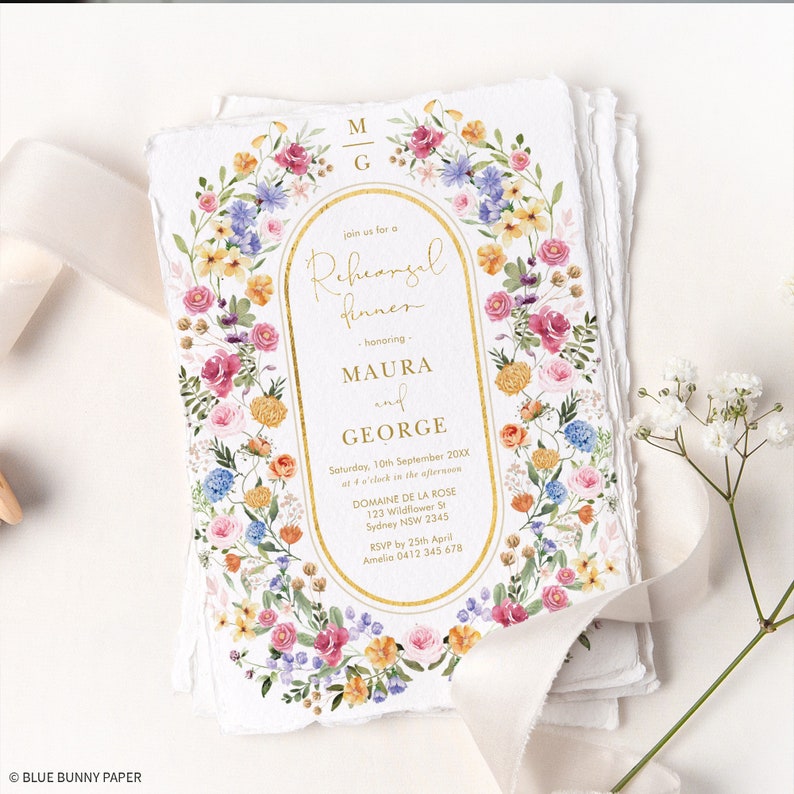 May include: A floral wedding rehearsal dinner invitation with a gold border and text. The invitation features the names Maura and George, the date and time of the event, and the location Domaine de la Rose. RSVP information is also included.