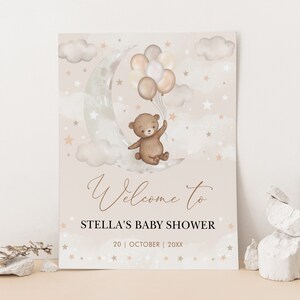 Może przedstawiać: Tablica powitalna na baby shower z brązowym pluszowym misiem trzymającym balony i siedzącym na rosnącym księżycu. Na tablicy widnieje napis "Witamy na baby shower Stell" oraz data "20 | PAŹDZIERNIK | 20XX".
