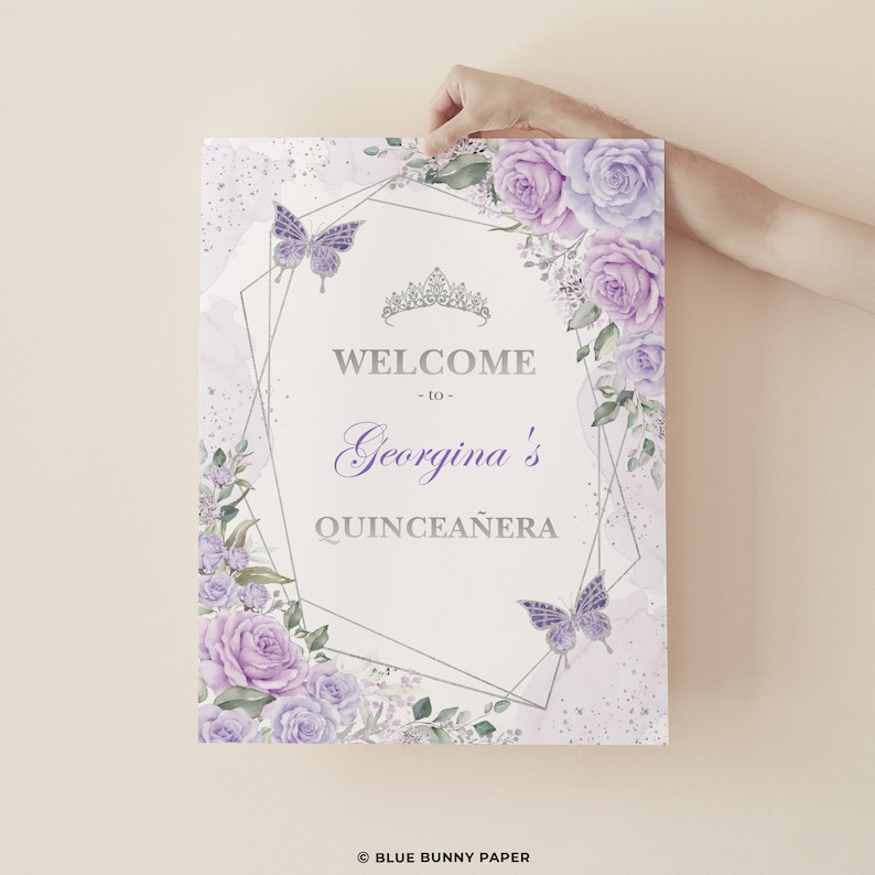 Puede incluir: Un cartel de bienvenida a la Quincea&ntilde;era de color morado y plateado con un marco geom&eacute;trico, detalles florales, mariposas y el texto "Bienvenido a la Quincea&ntilde;era de Georgina".