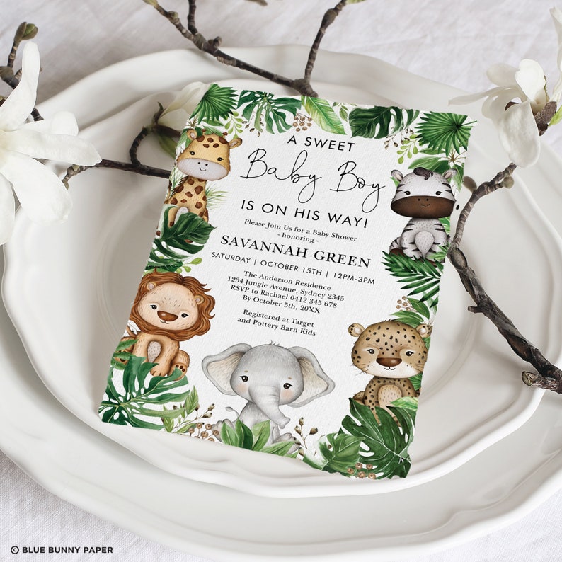 May include: A baby shower invitation with a jungle theme. The invitation features a green, leafy border with a variety of jungle animals, including a giraffe, zebra, lion, elephant, and leopard. The text on the invitation reads "A Sweet Baby Boy Is On His Way!" and includes the name "Savannah Green" and the date and time of the shower.