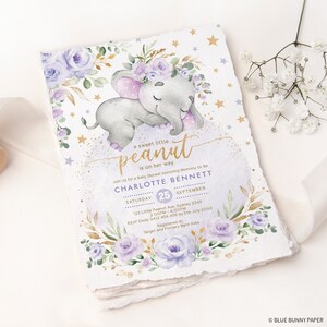 K&ouml;nnte beinhalten: Eine lila und goldene Babyparty-Einladung mit einer Aquarell-Illustration eines schlafenden Elefanten, der eine Blumenkrone tr&auml;gt. Der Text lautet "a sweet little peanut is on her way" und enth&auml;lt den Namen des Babys, Charlotte Bennett, sowie Datum und Uhrzeit der Party.