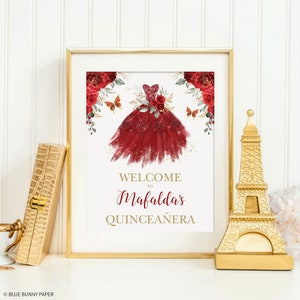 May include: A welcome sign for a Quincea&ntilde;era, featuring a red dress with gold glitter and red roses. The sign says "Welcome to Mafalda's Quincea&ntilde;era".