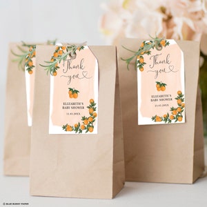 May include: Orange themed baby shower favor tags with the text "Thank you" and a heart. The tags feature a watercolor background with orange blossoms and leaves. The text "Elizabeth's Baby Shower" and the date "15.05.20XX" are also included.