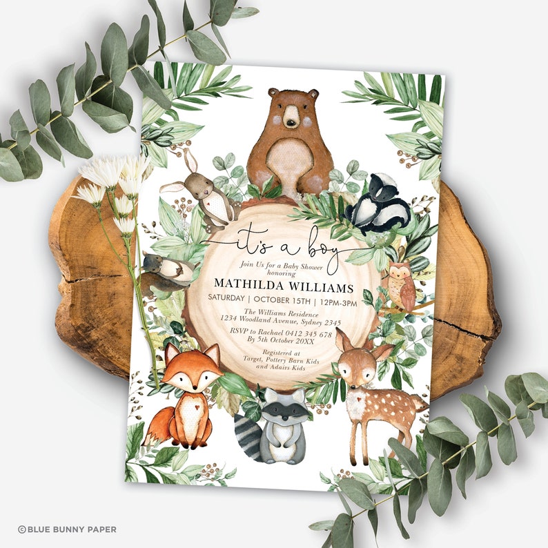 May include: A baby shower invitation with a woodland theme. The invitation features a variety of woodland animals, including a bear, a fox, a deer, a raccoon, a rabbit, an owl, and a skunk. The invitation is decorated with green leaves and branches. The text on the invitation reads "It's a boy!" and includes the name of the baby, the date and time of the shower, and the location.