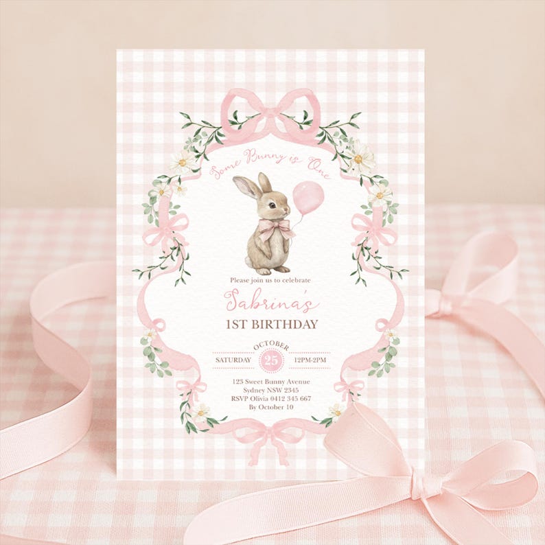 Op de afbeelding: Een roze en witte geruite uitnodigingskaart met een aquarel illustratie van een konijn met een roze ballon. De tekst luidt "Some Bunny is One" en "Sabrina's 1st Birthday". Roze strikken en bloemaccenten omlijsten de tekst.