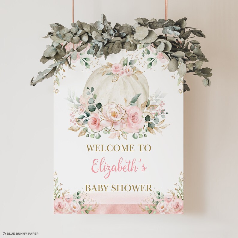 Puede incluir: Un cartel de bienvenida para un baby shower con una calabaza blanca decorada con flores rosas y doradas. El cartel dice "Bienvenido al baby shower de Elizabeth".