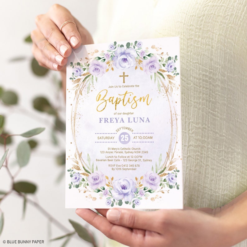 May include: A white and gold baptism invitation with purple flowers and a gold cross. The invitation reads "Join Us to Celebrate the Baptism of our daughter FREYA LUNA September 25 at 10:00AM St Mary's Catholic Church 123 Anzac Parade, Sydney NSW 2345 Lunch to Follow at 12:00PM Bavarian Beer Cafe - 123 George St, Sydney RSVP Eva 0412 345 678 By 10th September"