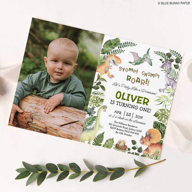 May include: A dinosaur-themed first birthday party invitation with a photo of a baby boy. The invitation features a green, brown, and purple dinosaur illustration with the text "Stomp! Chomp! Roar!! Let's Party Like a Dinosaur! Oliver is Turning One! Apr 25 | Sun at 2 o'clock in the afternoon The Williams Residence 123 Dinemite Road, Sydney 2345 RSVP Bettina 0412 345 678 By 10th October"