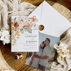 May include: A wedding invitation with a floral design in shades of orange, peach, and green. The invitation features the names "Candace and Alberto" and the wedding date "October 25th, 2028".
