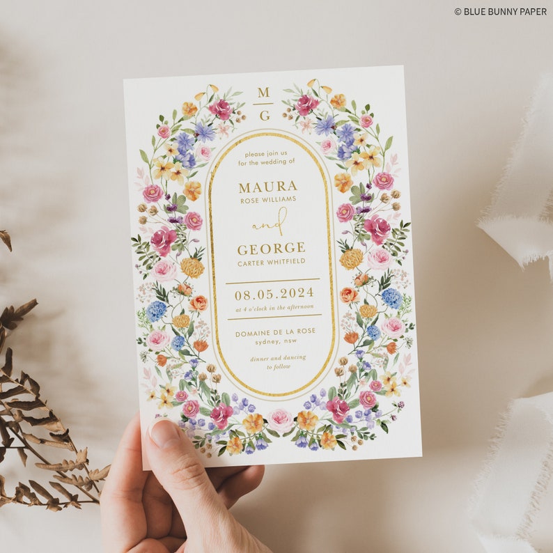 May include: Wedding invitation with a floral border in shades of pink, yellow, blue, and green. The invitation features the names Maura Rose Williams and George Carter Whitfield, the date 08.05.2024, and the location Domaine de la Rose, Sydney, NSW. The text is in gold lettering.
