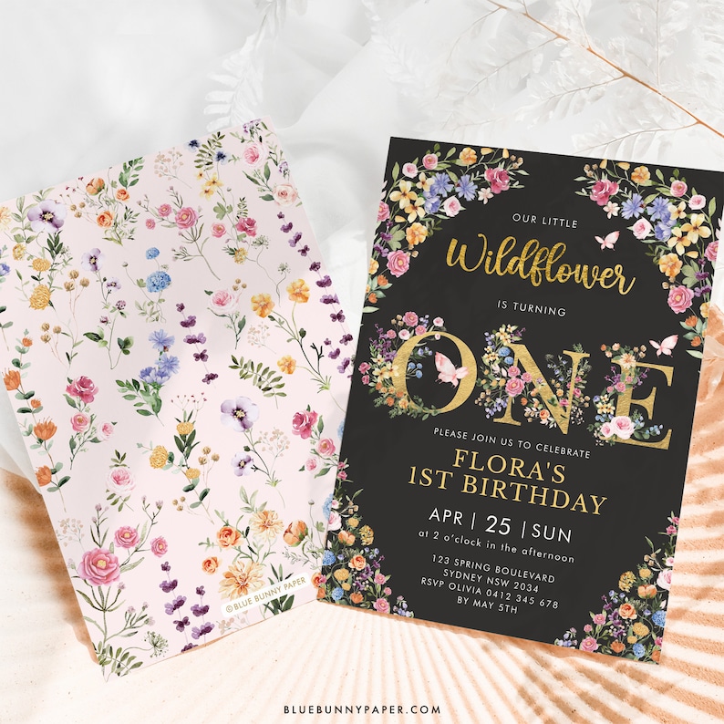 May include: A black and gold floral birthday invitation for a first birthday party. The invitation features a large gold "ONE" with floral accents and the text "Our Little Wildflower is Turning One". The invitation also includes the birthday girl's name, date, time, and location.