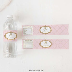 May include: Pink and gold water bottle labels with a crown and the text "Elizabeth's 1st Birthday 12.08.2023". The labels have a pink and white checkered pattern with gold accents.