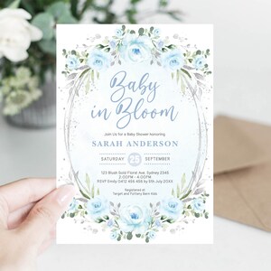 Peut inclure: Invitation de baby shower avec l'inscription "Baby in Bloom" en &eacute;criture cursive. Le design floral pr&eacute;sente des roses bleu clair et du feuillage, avec les d&eacute;tails de l'&eacute;v&eacute;nement.