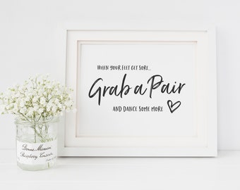 May include: White framed sign with black calligraphy text that reads "When your feet get sore... Grab a Pair and dance some more."  A small white heart is drawn next to the text.