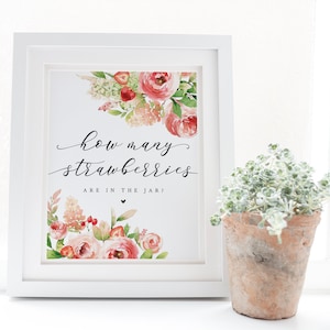 Könnte beinhalten: Ein weißer gerahmter Druck mit einem floralen Design und dem Text "Wie viele Erdbeeren sind im Glas?" in schwarzer Schrift. Das florale Design zeigt rosa und rote Blumen, grüne Blätter und rote Erdbeeren.
