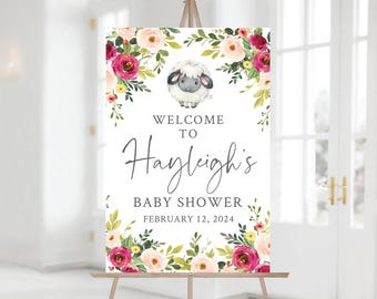 May include: Welcome to Hayleigh's Baby Shower sign with a floral wreath and a cute cartoon lamb. The sign is white with gray text and a date of February 12, 2024.