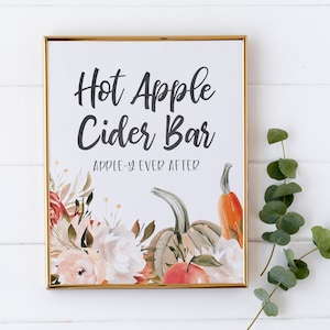 May include: A printable sign with a gold frame, featuring a watercolor illustration of pumpkins, apples, and flowers. The sign reads "Hot Apple Cider Bar" with the tagline "Apple-y Ever After".