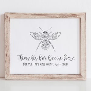 May include: A framed print with a black and white illustration of a bee with the text "Thanks for beein here. Please take one home with you."